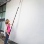 Frau nutzt Gardena combisystem Winkelbesen mit Stiel zur Reinigung einer Dachrinne.