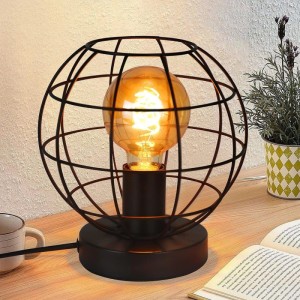 Schwarze Vintage Tischlampe mit rundem Metall-Käfigschirm und leuchtender E27 Edison Glühbirne auf Holztisch.