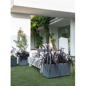 Aschgrauer Deroma Pflanzkasten Cosmo 78 cm mit Pflanzen auf einer Terrasse.