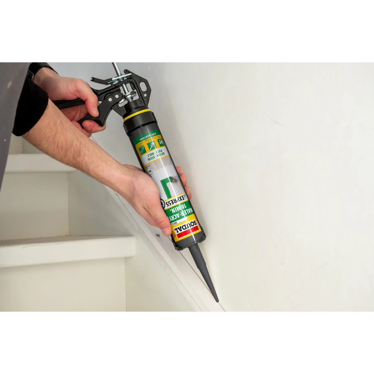 Person dichtet Fuge an weißer Treppe mit Soudal Maleracryl 10 min-Express Weiß ab. Acryl-Dichtstoff für Fugen.