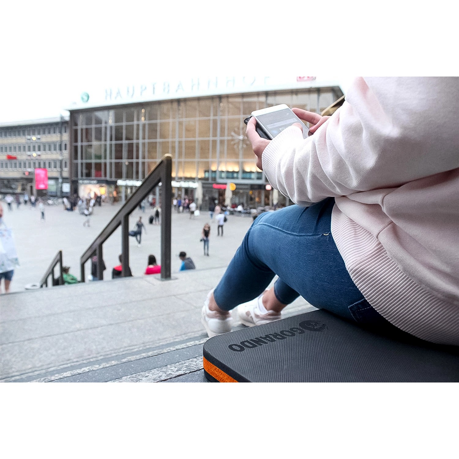 Person sitzt auf Gorando Premium Kniekissen (2er Set) auf Treppe in der Stadt.