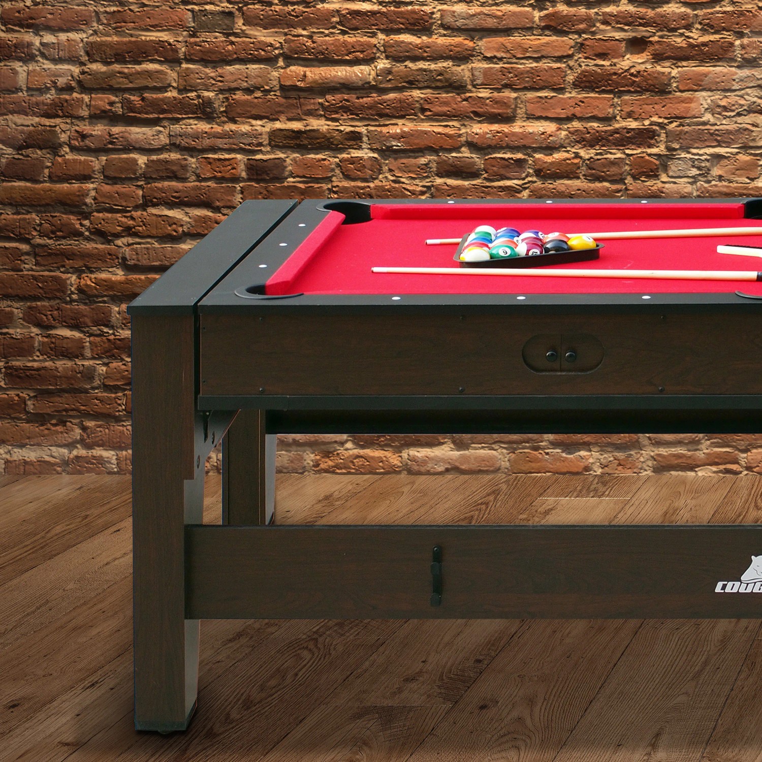 Spieltisch Reverso als Pooltisch mit rotem Tuch, Queue und Billardkugeln.