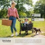Faltbarer, schwarzer Tectake Bollerwagen mit Kind, Hund und Picknick-Korb im Grünen.