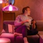 Mann steuert Philips Hue Leuchten mit dem Smartphone im Wohnzimmer.
