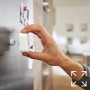 Hand befestigt Philips Hue Bewegungssensor an Metalloberfläche. Teil des Lightstrip Flux Bundle.