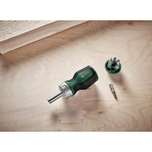 Bosch Bit-Ratschenschraubendreher Stubby mit 6 Bits, grün-schwarz, mit Bit-Magazin und einem Bit auf Holz.