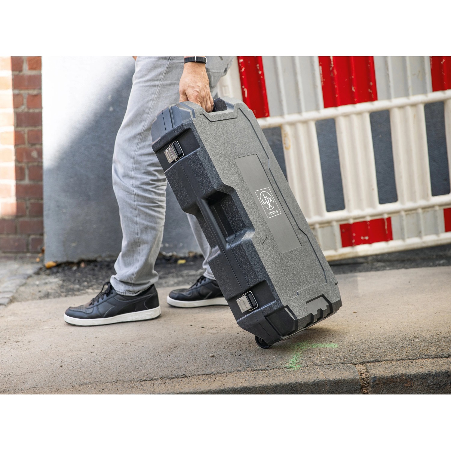 Mann zieht Transportbox für LUX-TOOLS Abbruchhammer E-ABH-1700 hinter sich her.