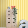 ESTAhome Vliestapete mit gelben Streifen an einer Wand, kombiniert mit Möbeln und Deko.