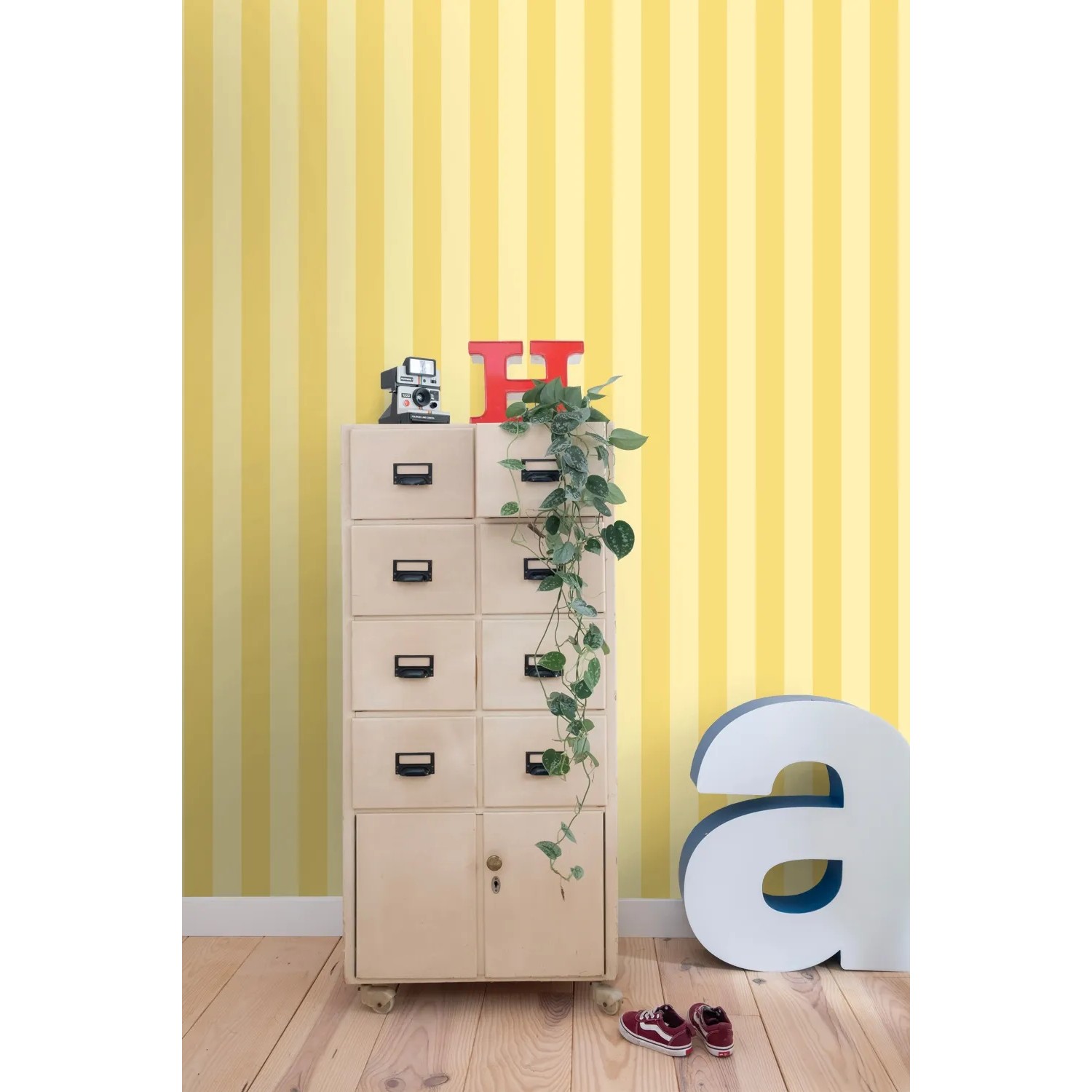 ESTAhome Vliestapete mit gelben Streifen an einer Wand, kombiniert mit Möbeln und Deko.