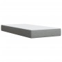 Hellgraues Boxspringbett 90x200 cm mit Matratze und Auflage.
