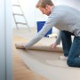 Mann rollt LUX Auslegepapier zum Schutz bei Renovierungsarbeiten aus.