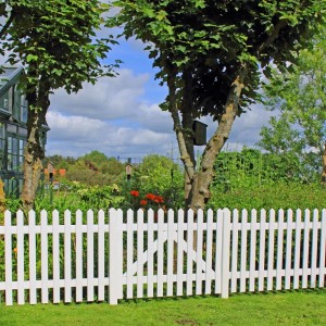 Weißes Gartentor Skagen Lux aus Nadelholz, 100x80 cm, vor Gartenlandschaft.