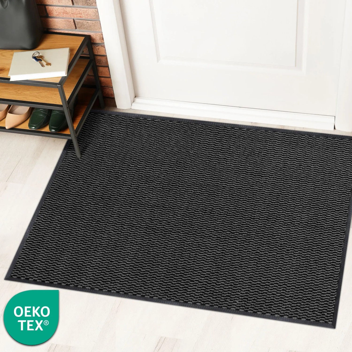 Anthrazitfarbene KARAT Schmutzfangmatte SKY Novo (90x120 cm) mit TPE-Rücken vor einer Tür.