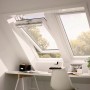 VELUX Schwingfenster F04 aus Kunststoff, geöffnet in Dachschräge über Schreibtisch.
