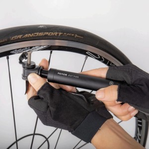 Schwarze Topeak Roadie 2Stage Handpumpe wird an Rennradreifen befestigt. Kompakte Luftpumpe für Fahrradreifen.