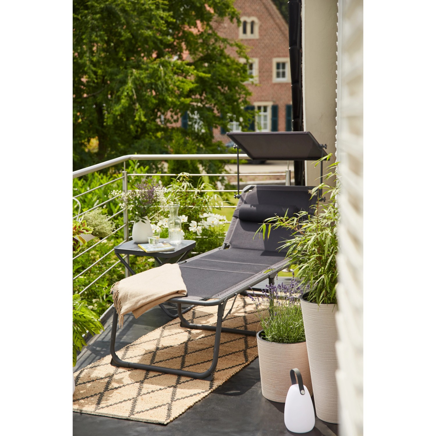Anthrazitfarbene Siena Garden Campingliege Premium mit verstellbarem Sonnendach auf Balkon.