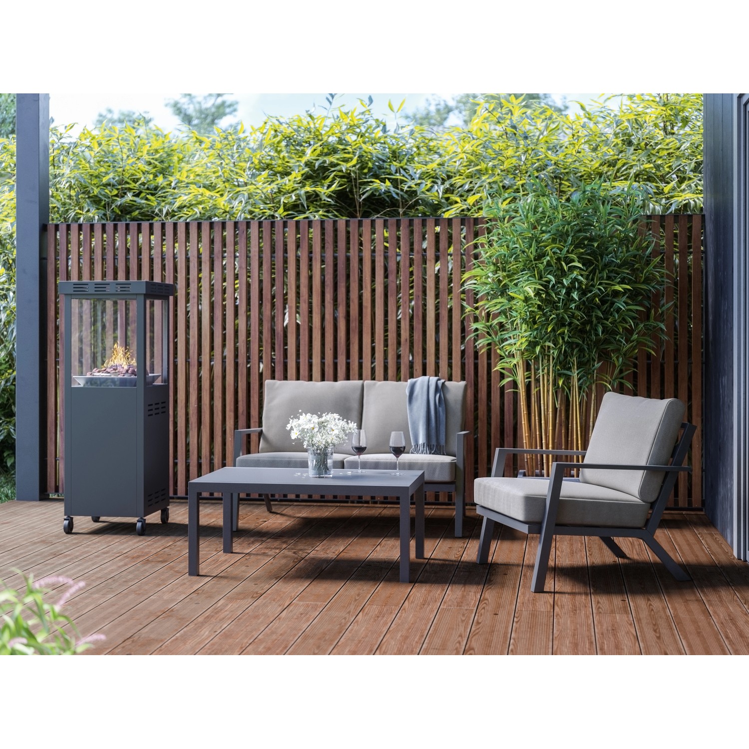 Anthrazitfarbener Gaskamin Ridera 6,5 kW mit Panoramaglas und Deko-Steinen auf einer Terrasse mit Sitzmöbeln.