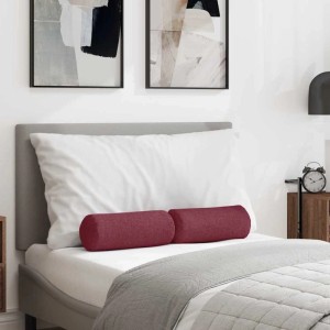 Zwei weinrote Stoff Bolsterkissen auf einem Bett mit weißem Kissen und grauer Decke im Schlafzimmer.