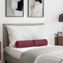 Zwei weinrote Stoff Bolsterkissen auf einem Bett mit weißem Kissen und grauer Decke im Schlafzimmer.