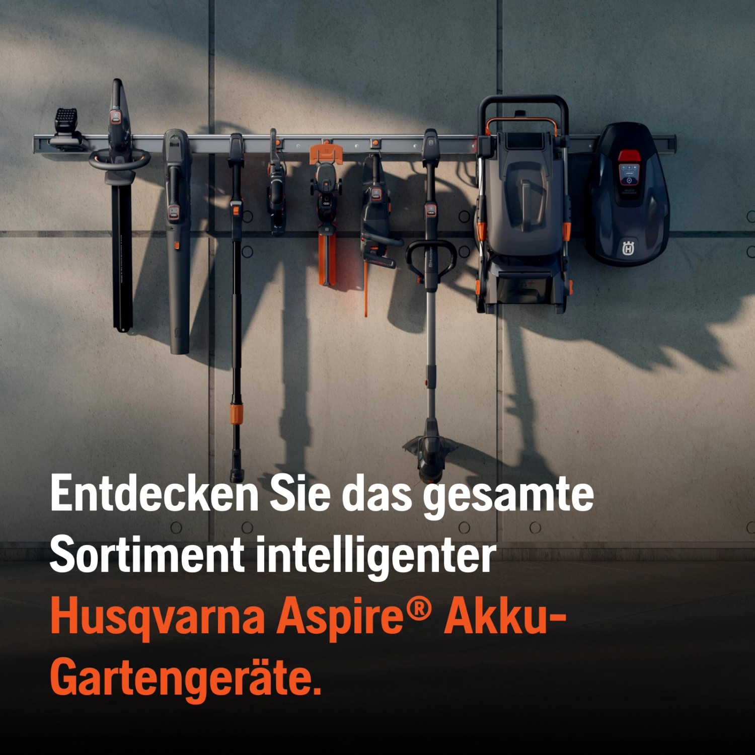 Husqvarna Aspire Akku-Gartengeräte an einer Schiene: Heckenschere, Rasentrimmer, Grasschere, Mähroboter.