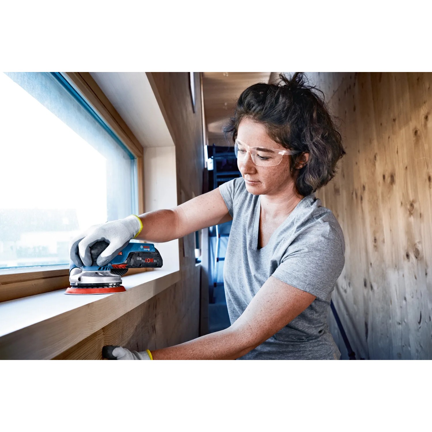 Frau schleift Fensterrahmen mit Bosch Professional Akku-Exzenterschleifer GEX 18V-125.