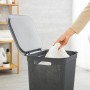 Anthrazitfarbener Rotho Wäschesammler Brisen (50 l) mit Deckel und Wäscheeinfüllung.