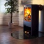 Schwarze, halbkreisförmige Tulup Glasplatte als Kamin-Bodenschutz unter einem Kaminofen.