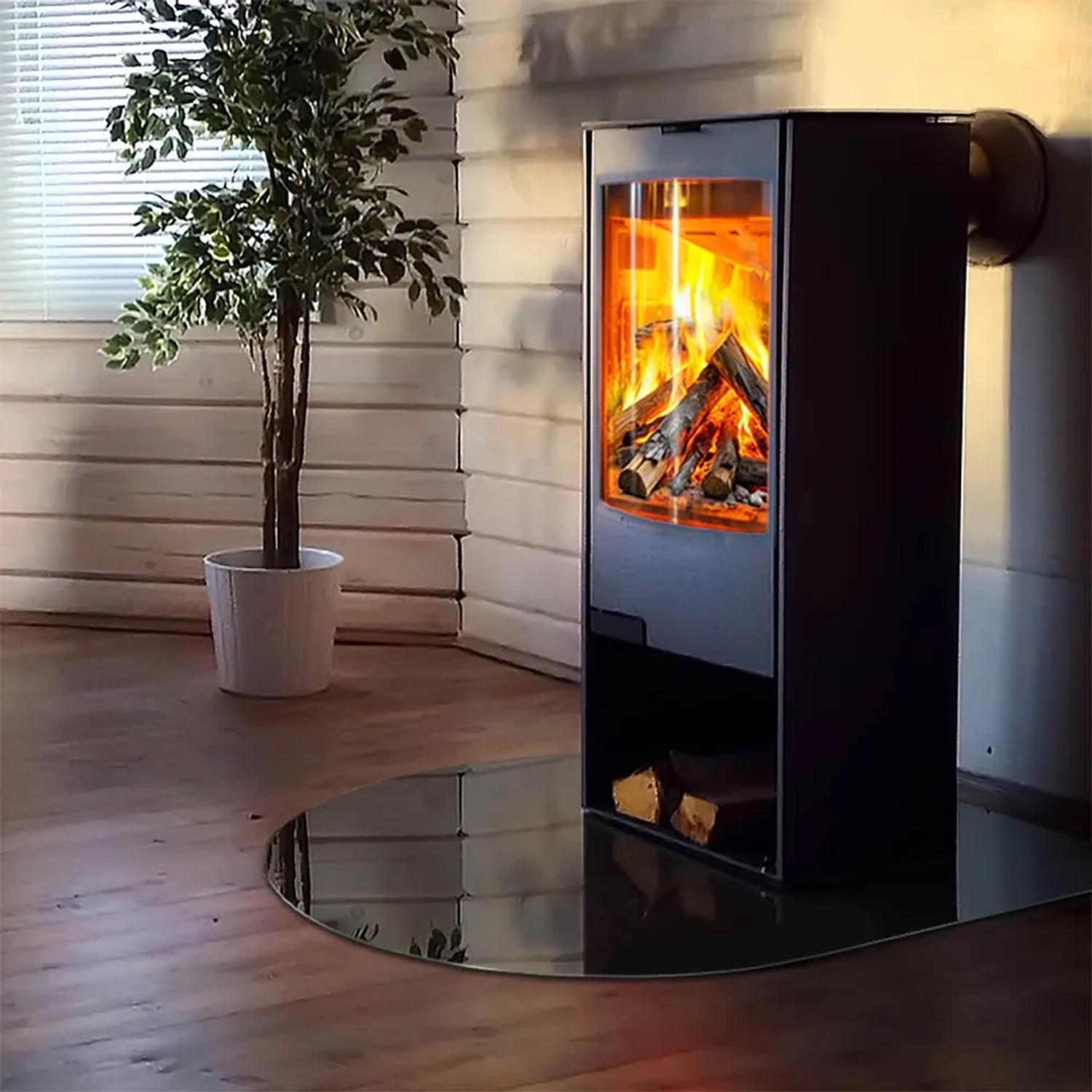 Schwarze, halbkreisförmige Tulup Glasplatte als Kamin-Bodenschutz unter einem Kaminofen.
