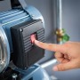 Detailaufnahme: Hand betätigt Schalter am Hauswasserwerk 1100 W HWW 4600/E.
