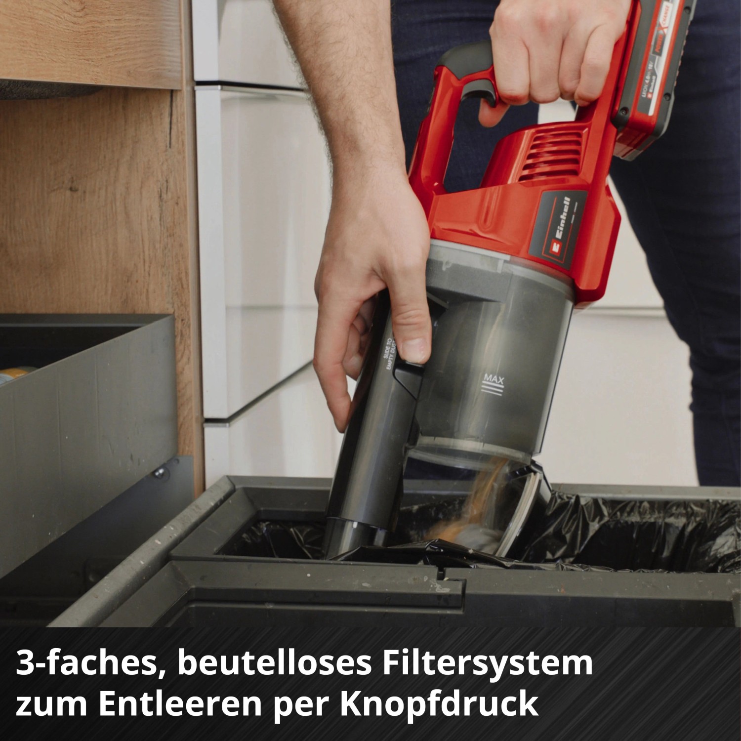 Einhell Akku-Stielstaubsauger wird entleert. Beutelloser Staubbehälter mit Schmutz über Mülleimer.