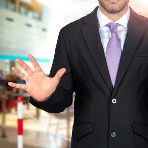 Mann stoppt mit Handgeste vor rot-weißem Absperrpfosten. Ideal für Absperrungen und Markierungen.