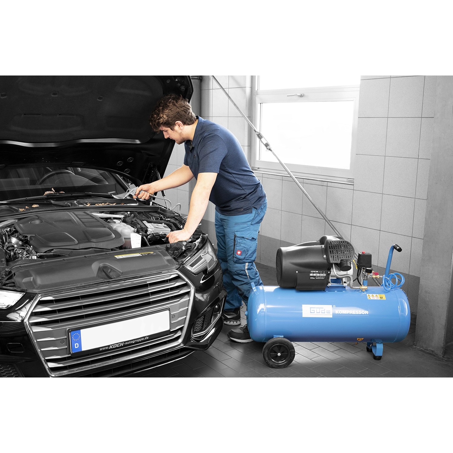 Blauer Güde Kompressor 412/8/100 bei der Nutzung an einem Auto.