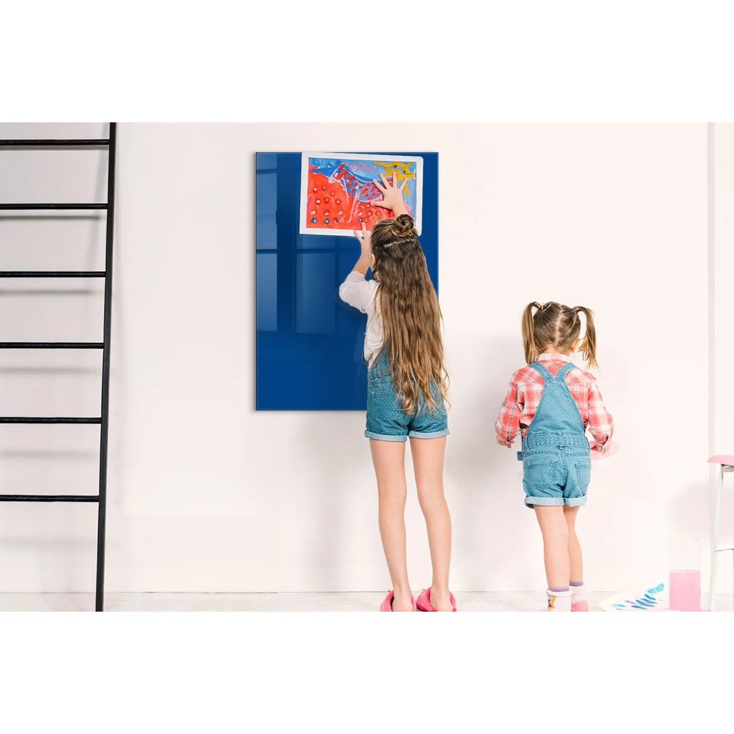 Blaue Glas Magnettafel (70x100 cm) mit Kindern, die ein Bild befestigen. Ideal als Whiteboard für Notizen.