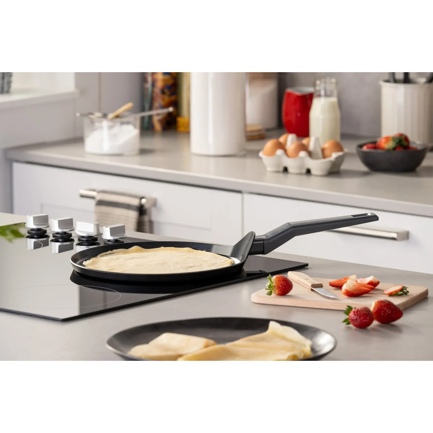 Fackelmann Crepepfanne Statement 25 cm auf Induktionsherd mit fertigem Crepe und Erdbeeren.