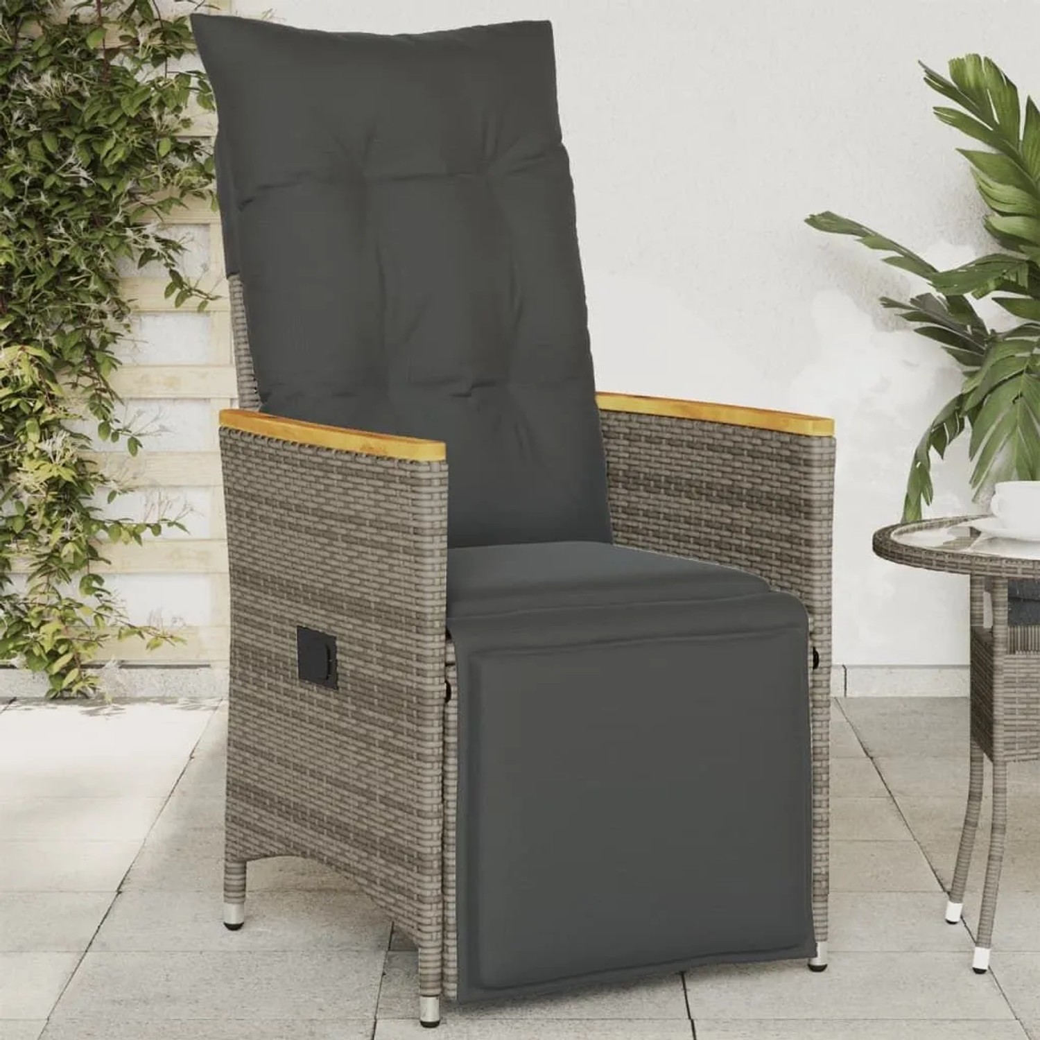 Grauer verstellbarer Poly Rattan Gartensessel mit dunklen Kissen und Holzarmlehnen auf Terrasse.