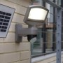 Lutec Solar LED-Strahler Sunshine mit Solarpanel an einer Wand. Außenstrahler mit Bewegungssensor.