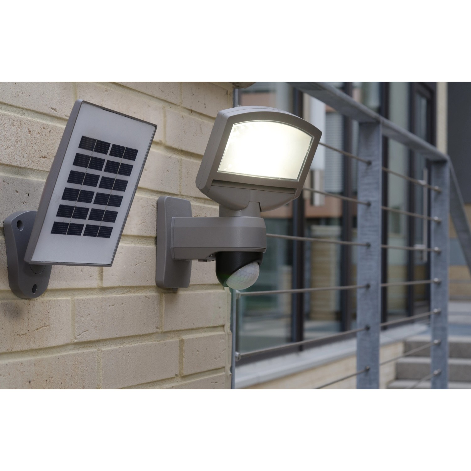 Lutec Solar LED-Strahler Sunshine mit Solarpanel an einer Wand. Außenstrahler mit Bewegungssensor.