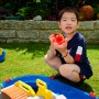 Kind spielt mit AquaPlay MountainLake Wasserbahn. Buntes Spielset mit Boot und Spielfigur im Garten.