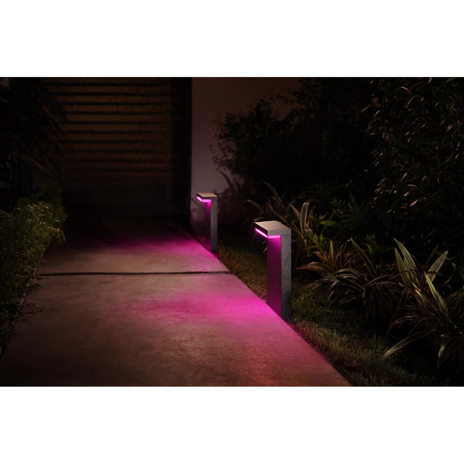 Philips Hue Nyro Sockelleuchte, schwarz, mit farbigem Licht im Garten.