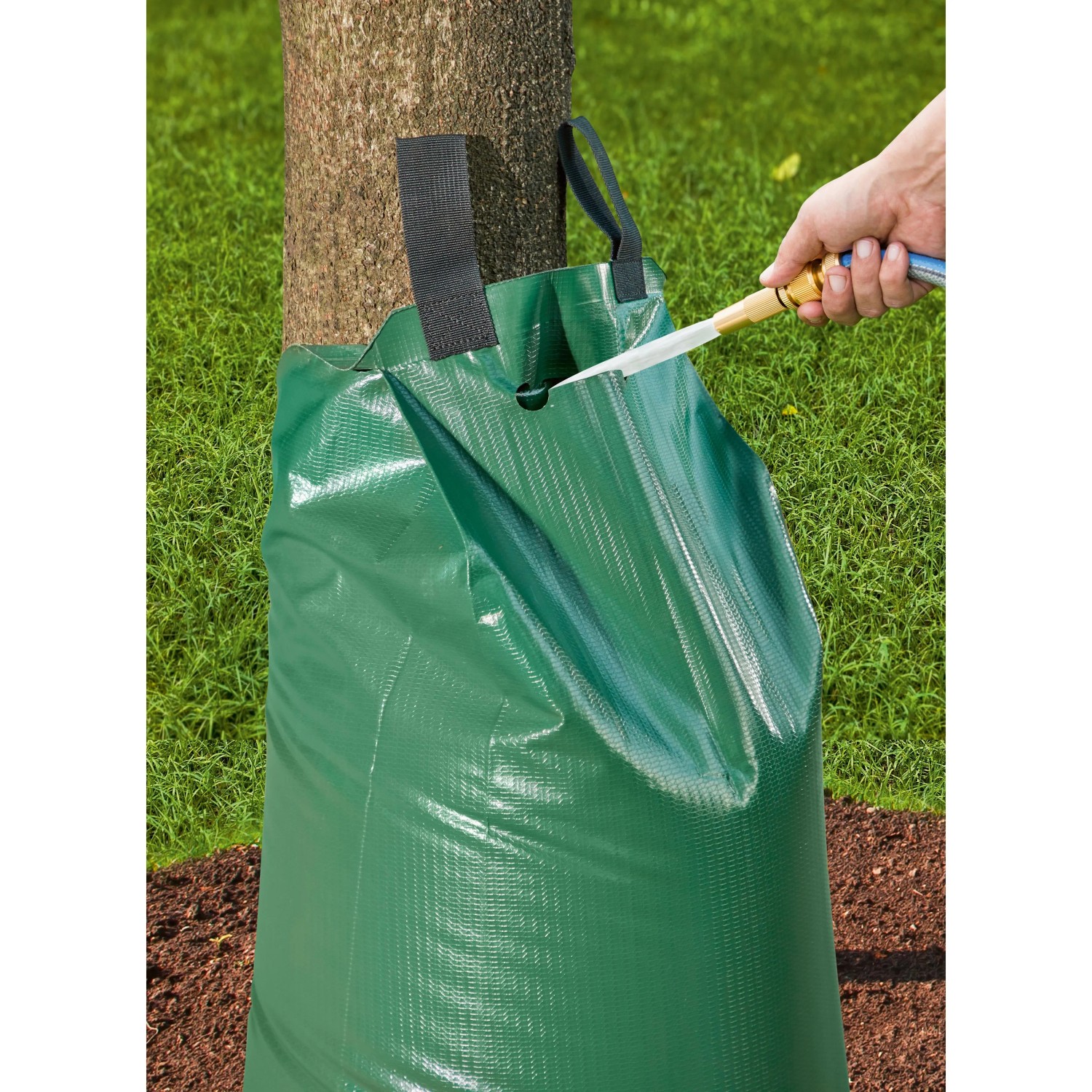 Grüner 100 l Tropfbewässerungssack am Baumstamm beim Befüllen.