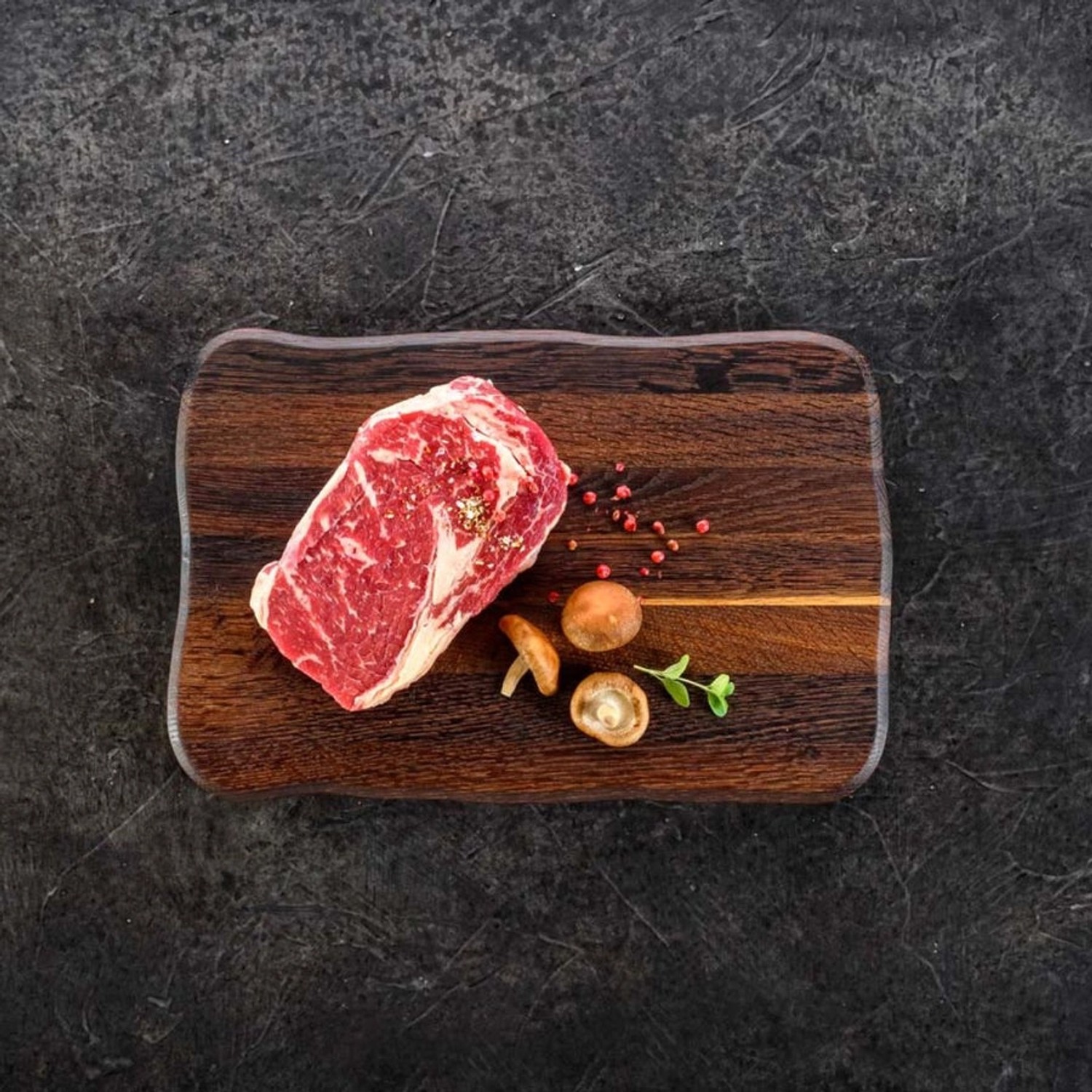 Dunkles Eiche Schneidebrett mit Steak, Pilzen und Gewürzen. holz4home La Madera.