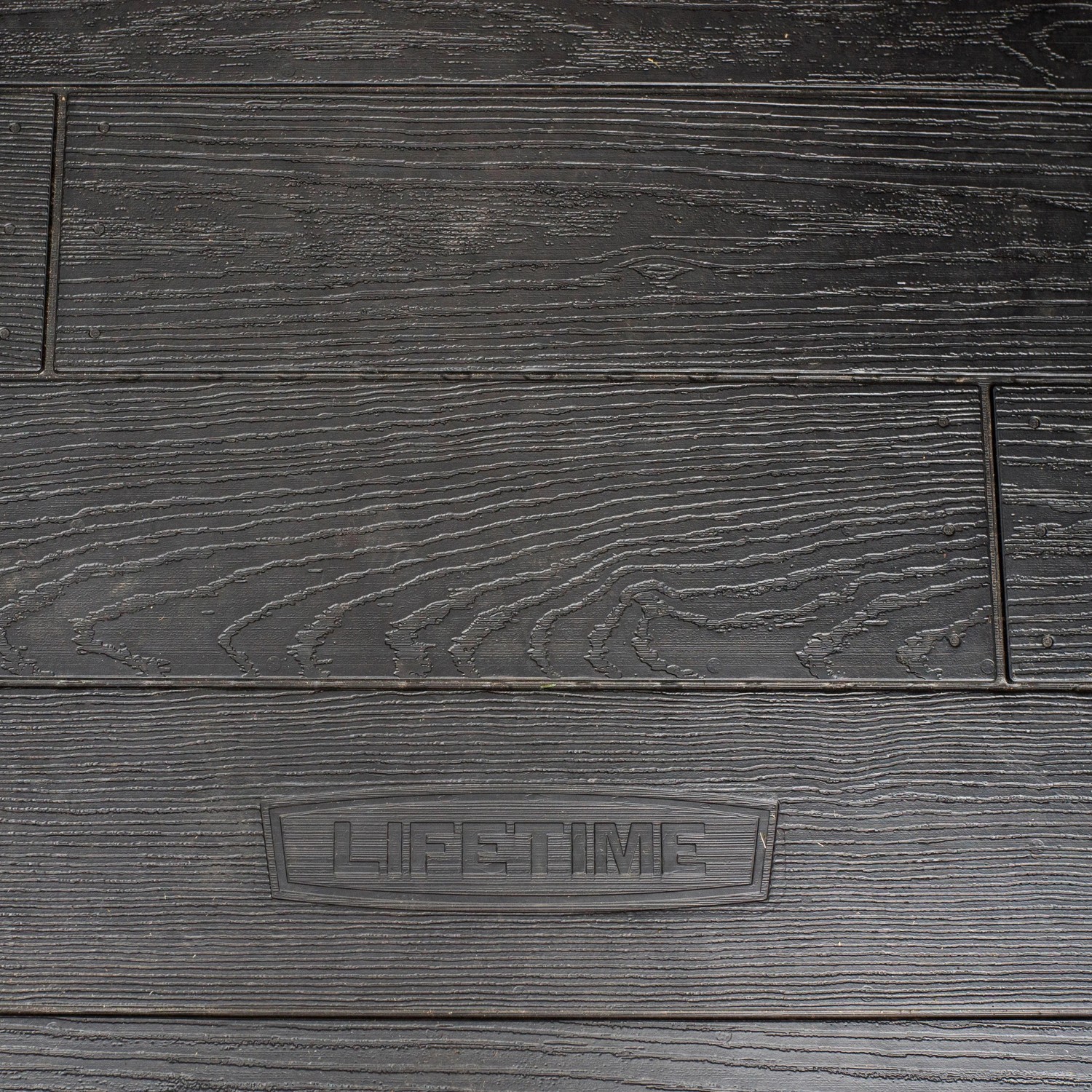 Detailaufnahme: Schwarzes Lifetime Kunststoff-Gartenhaus Stella mit Holzstruktur.
