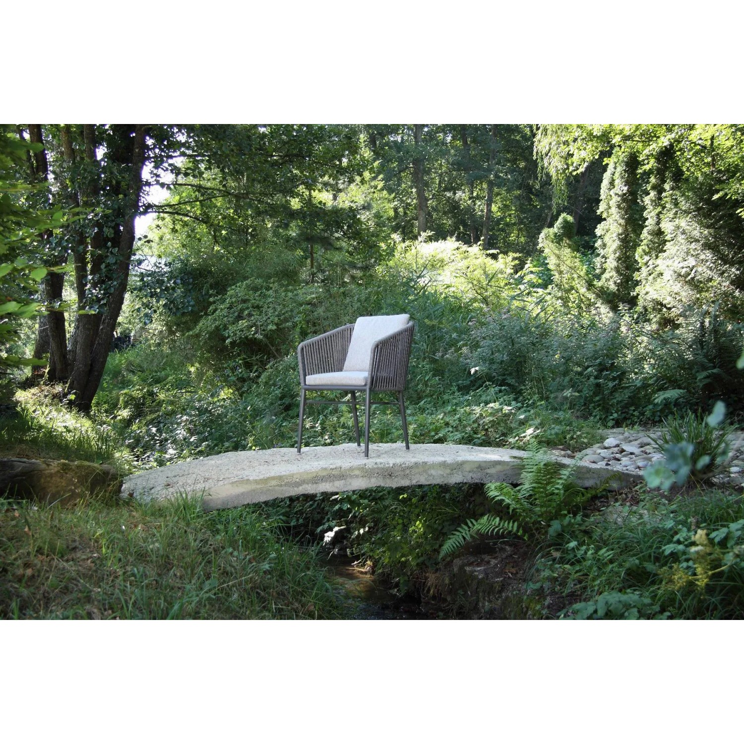 Anthrazitfarbener Acamp Manhattan Armsessel mit Kissen im Garten.