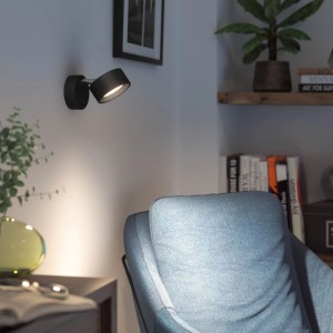 Schwarze Philips Bracia 1-flammige LED-Spotleuchte an der Wand, beleuchtet gemütlichen Wohnbereich mit warmweißem Licht.
