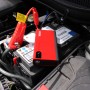 Rotes Mini Lithium Power Pack 200A mit Krokodilklemmen und LED-Arbeitsleuchte auf Autobatterie.