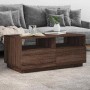 Moderner Couchtisch in Braun Eichen-Optik mit offenen Fächern und Stauraum, vor grauem Sofa im Wohnzimmer.