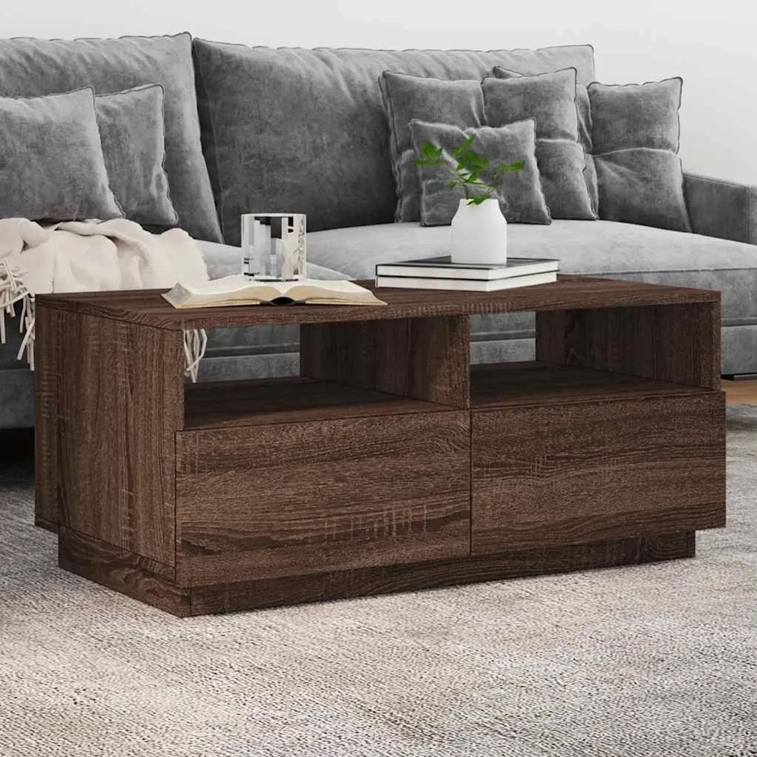 Moderner Couchtisch in Braun Eichen-Optik mit offenen Fächern und Stauraum, vor grauem Sofa im Wohnzimmer.