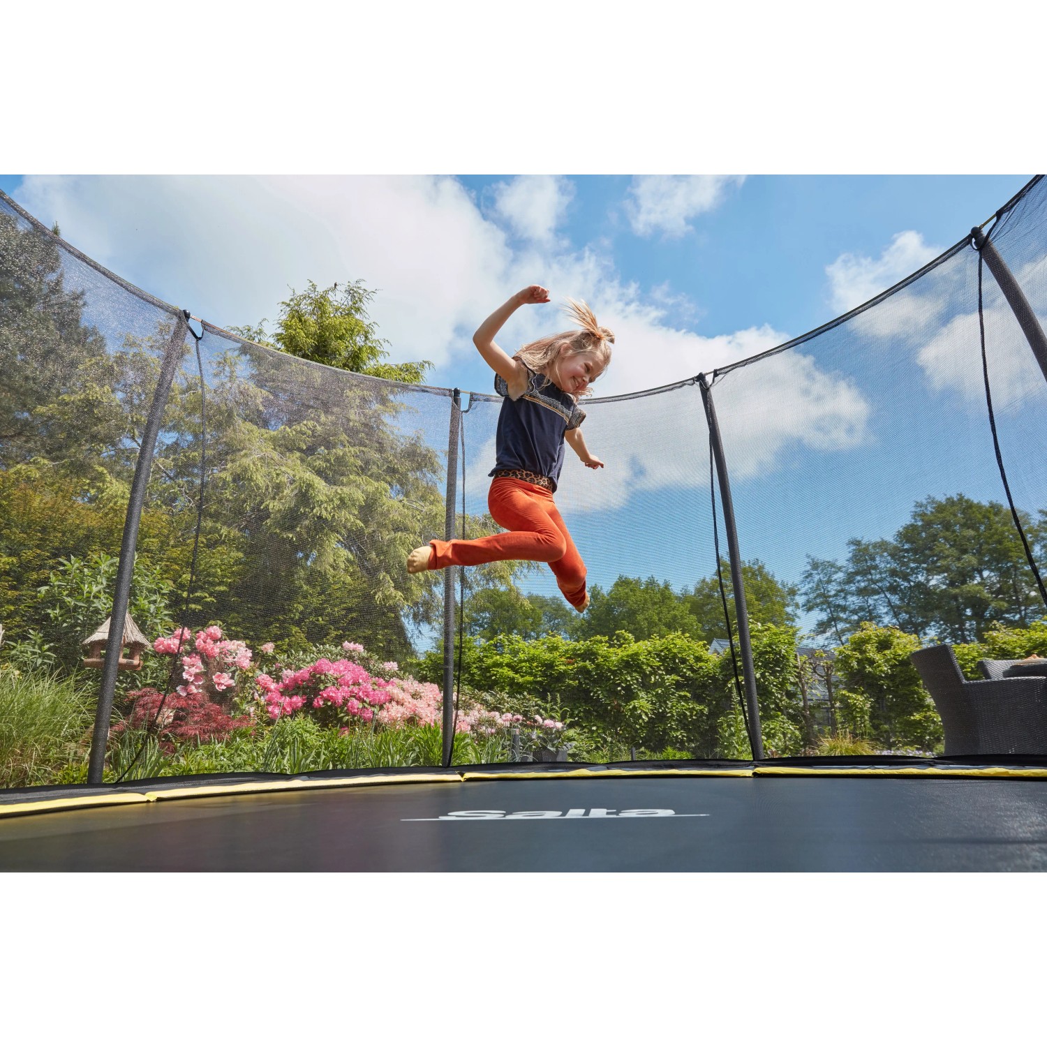 Kind springt auf schwarzem Salta Bodentrampolin Comfort Edition ø 213 cm mit Sicherheitsnetz.