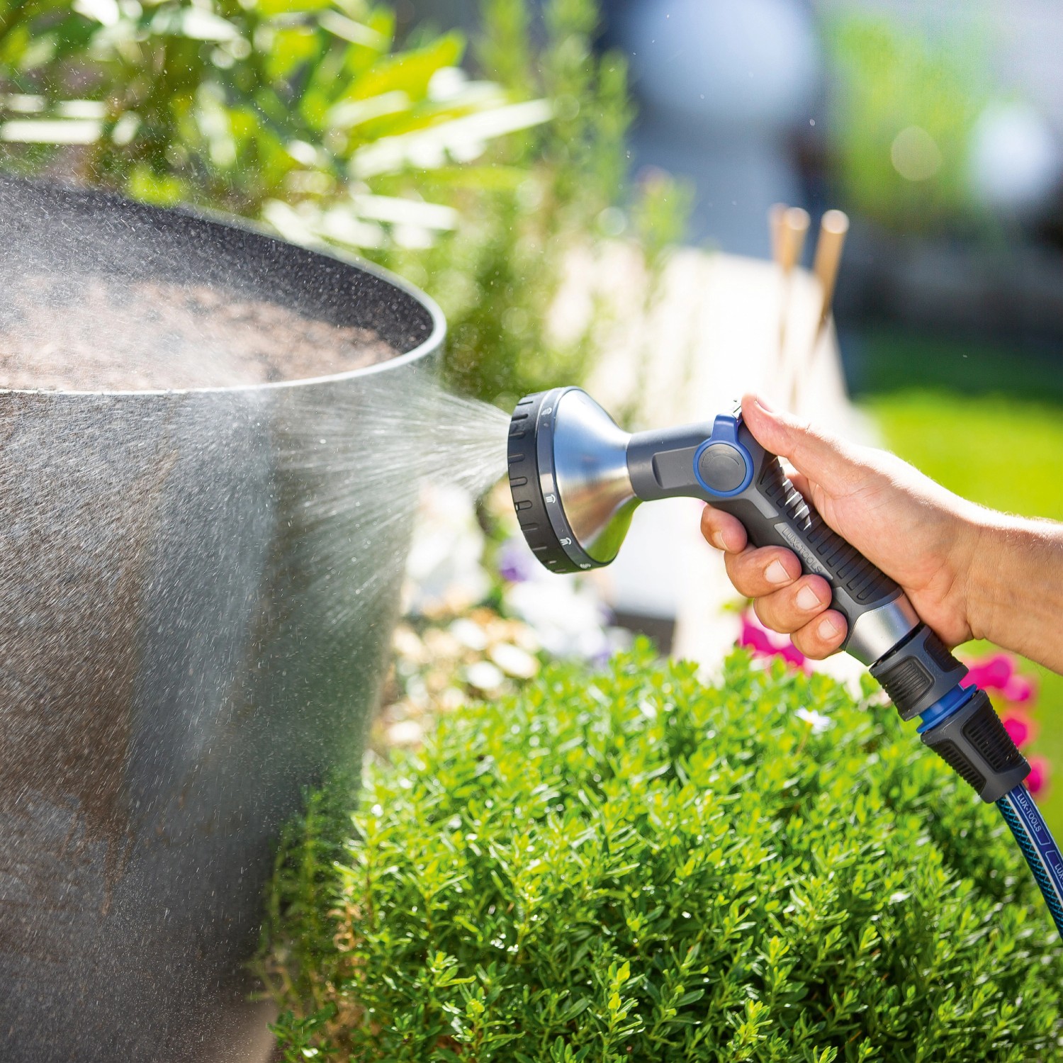 LUX Multifunktionsbrause mit 10 Strahlvarianten beim Bewässern einer Pflanze im Garten.