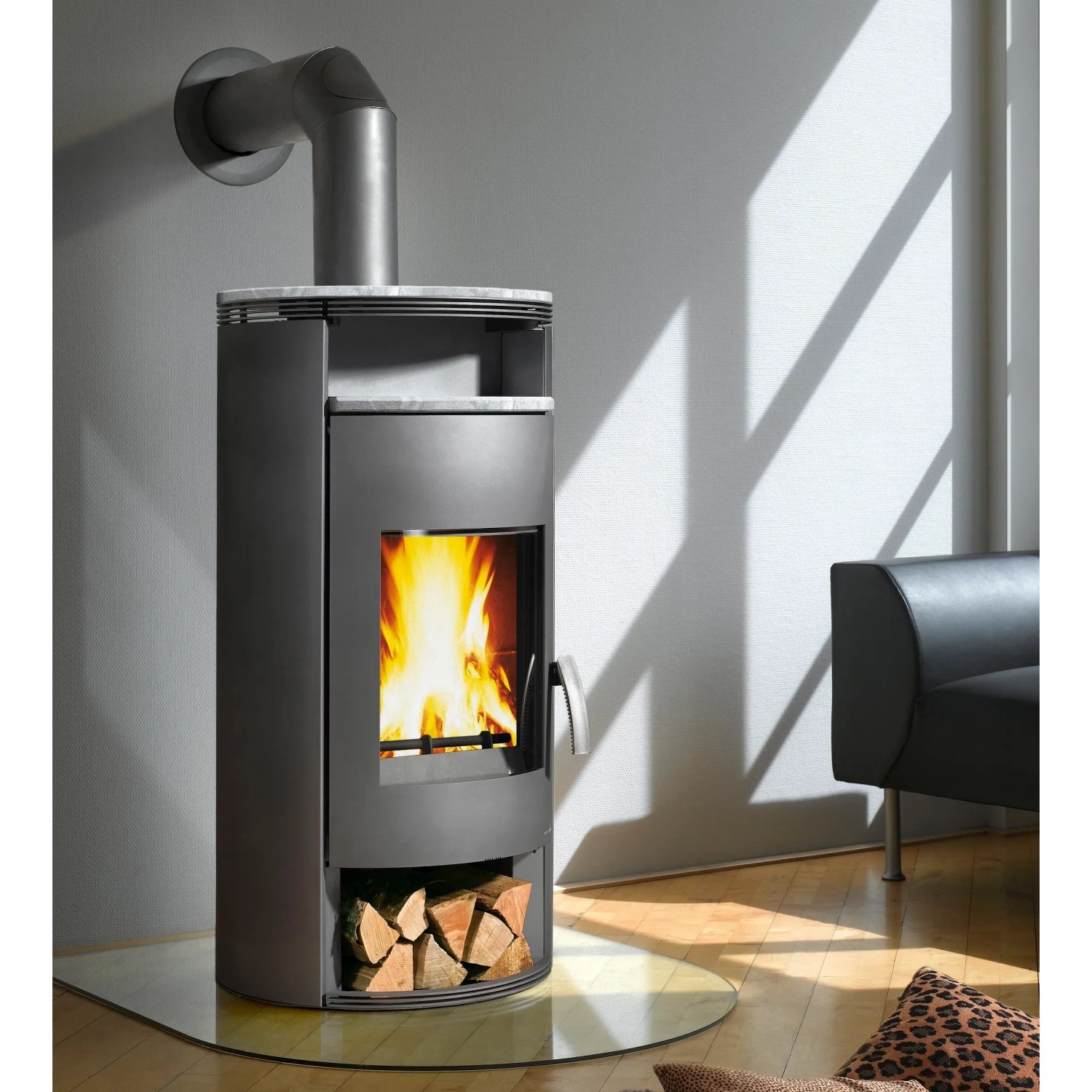 Grauer Wamsler Atlas Kaminofen (8 kW) mit Holzscheiten im Lagerfach. Zeitbrandofen für gemütliche Wärme.
